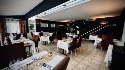 une salle à manger avec des tables et des chaises blanches dans l'établissement Logis Le Relais de la Voie Sacrée, à Issoncourt