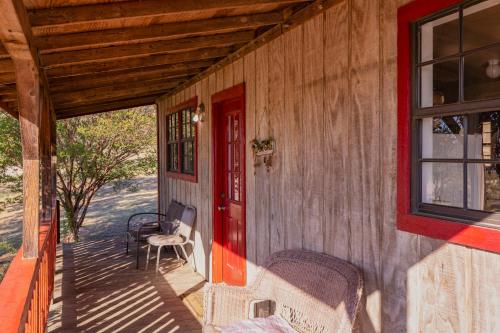 a porch of a house with a red door and a chair at Hi-Line Resort in Tow