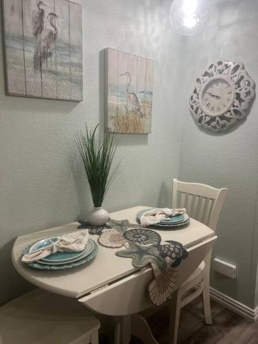 a dining room table with plates and a clock on the wall at Casa Del Marlin - Your Beach Retreat on Galveston Island, TX in Galveston