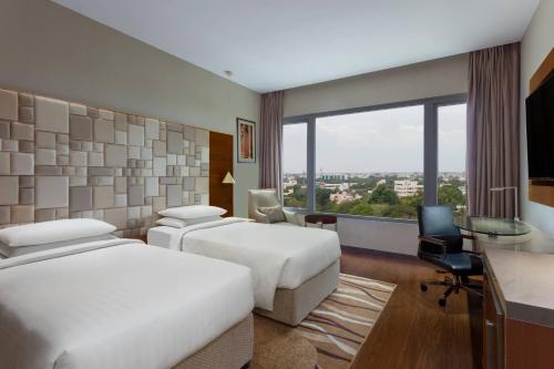 una camera d'albergo con due letti, una scrivania e una finestra di Courtyard by Marriott Madurai a Madurai