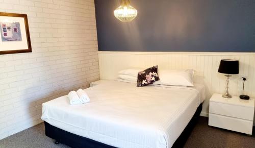 a bedroom with two beds with white sheets and a lamp at Motel Sierra - Bright in Bright