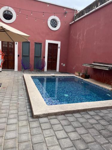 a swimming pool in front of a red building at Quinta La Perla in Guadalajara