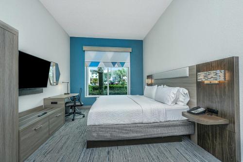 a bedroom with a bed and a desk with a television at Holiday Inn Express & Suites Charleston Arpt-Conv Ctr Area by IHG in Charleston