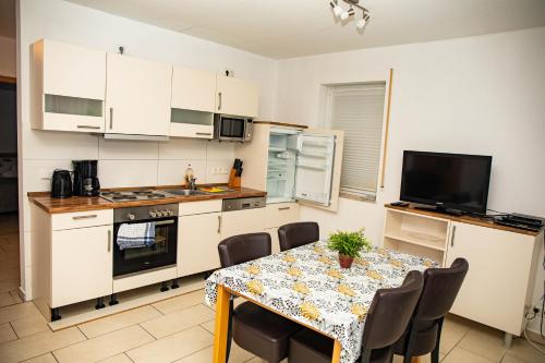 a kitchen with a table and a kitchen with white cabinets at Ferienwohnungen Saida Wohnung 9 in Norden