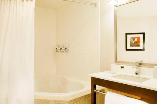 a white bathroom with a tub and a sink at Four Points by Sheraton Newark Christiana Wilmington in Newark