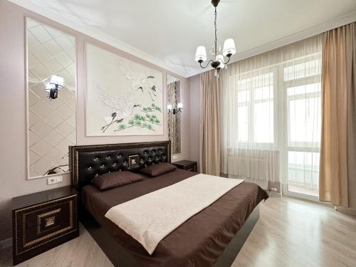 - une chambre avec un grand lit et un lustre dans l'établissement 2-комнатные апартаменты в жилом комплексе Zaman, à Atyraū