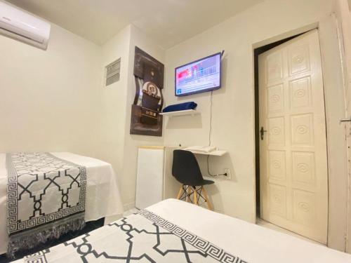a room with two beds and a door and a television at Pousada Açude Velho in Campina Grande