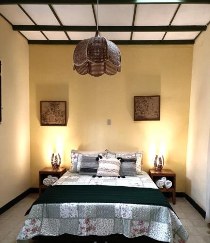 a bedroom with a large bed and a chandelier at Posada Las Bromelias in Silvania