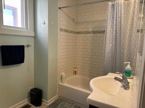 La salle de bains blanche est pourvue d'un lavabo et d'une baignoire. dans l'établissement Lyndale Oasis, à Minneapolis