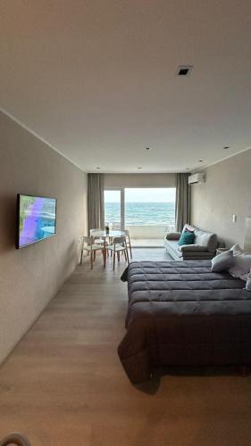 1 dormitorio con cama, sofá y mesa en Quequen frente al mar con pileta climatizada en Quequén