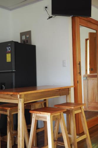 a wooden table with chairs and a black refrigerator at Bungalows Paraíso Celeste in Bijagua