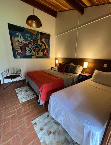 a bedroom with two beds and a painting on the wall at Hotel Casa Paradiso Guarujá in Guarujá