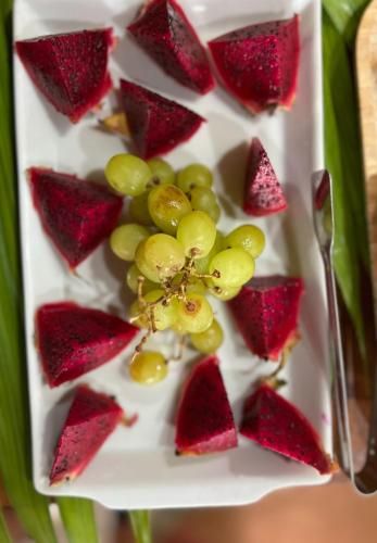 a plate with strawberries and grapes and a fork at Hotel Casa Paradiso Guarujá in Guarujá