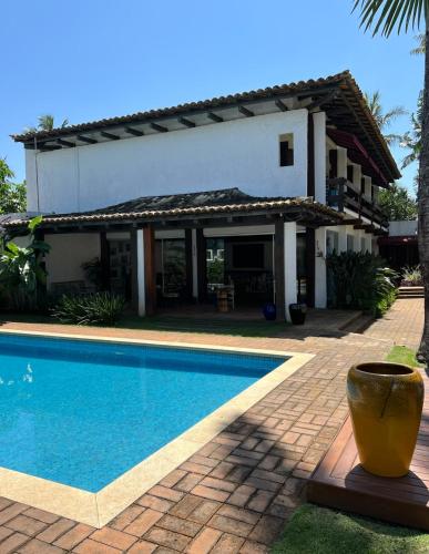 a villa with a swimming pool in front of a house at Hotel Casa Paradiso Guarujá in Guarujá