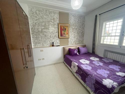 a bedroom with a purple bed and a window at APPART SARAH Plage in Hammamet Nord