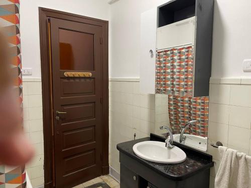 La salle de bains est pourvue d'un lavabo et d'une porte marron. dans l'établissement Wonderful Apartment Place in Dokki, au Caire