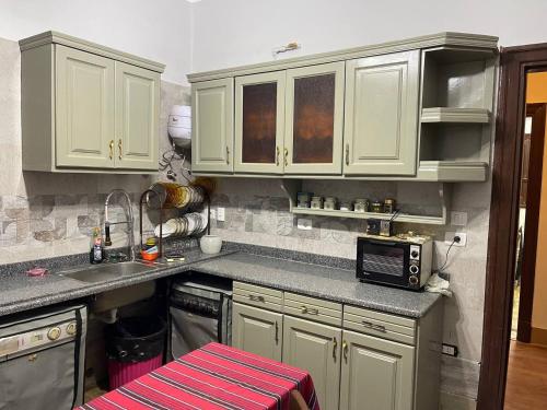 una cucina con armadi bianchi, lavandino e forno a microonde di Wonderful Apartment Place in Dokki a Il Cairo