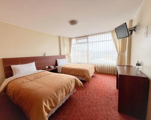 Habitación de hotel con 2 camas y TV de pantalla plana. en HOTEL FLOR DE LOS ANDES en Tulcán