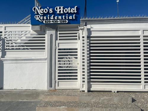 um portão branco em frente a um edifício com uma placa em Neo’s hotel em Santa Cruz de Barahona