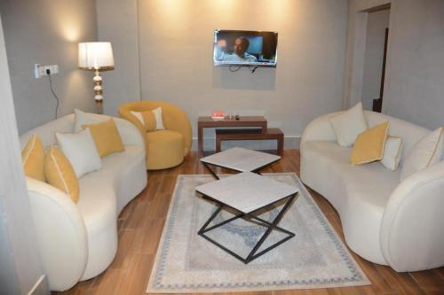 a living room with two white couches and a tv at أجنحة هدوء الفندقية in Riyadh