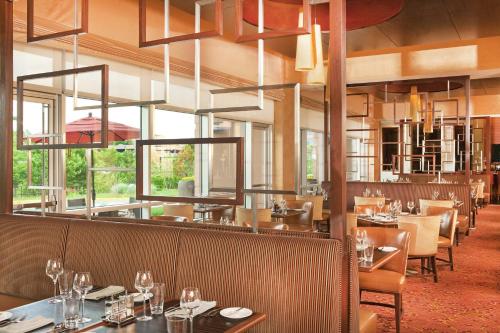 a dining room with tables and chairs and windows at The Westin Washington Dulles Airport in Herndon