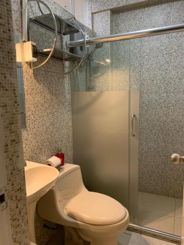 a bathroom with a toilet and a glass shower at Central boutique Trujillo in Trujillo