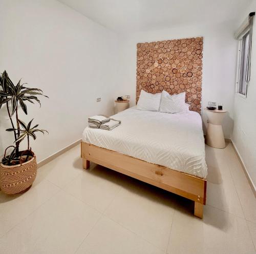 ein Schlafzimmer mit einem Bett und einer Topfpflanze in der Unterkunft Playa del Hombre Deluxe Luxury Apartments in Playa del Hombre