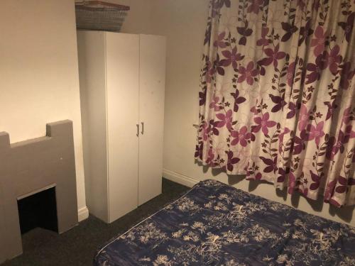 1 dormitorio con cama, cortina y chimenea en Comfy keats place en Bushbury