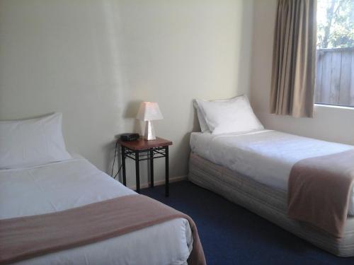 a hotel room with two beds and a table with a lamp at South Park Motel in Masterton