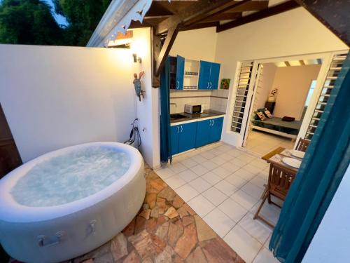 a bath tub in a bathroom with a kitchen at Mabouya cosy vue mer, jacuzzi, jardin in Sainte-Luce