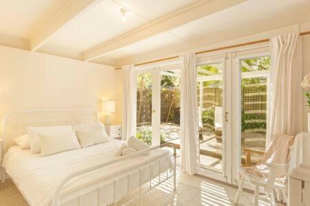 een witte slaapkamer met een bed en een groot raam bij Kilara Cottage 3-Bed 2-Bath in Cowes