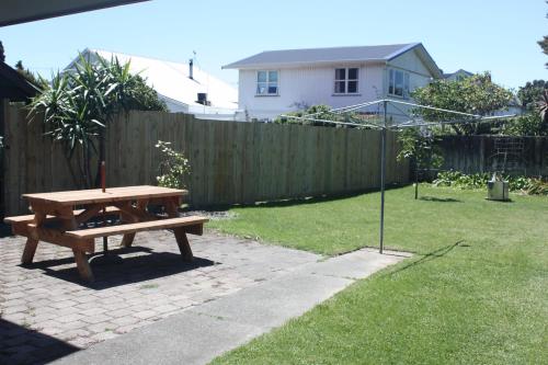 a wooden picnic table in a backyard with a fence at Esplanade Townhouse in Gisborne