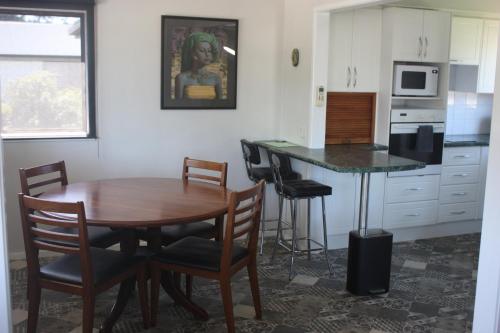 a kitchen with a wooden table and chairs and a counter at Esplanade Townhouse in Gisborne