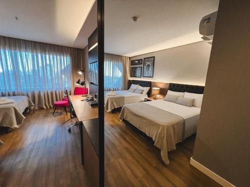 a hotel room with two beds and a desk at Quartos no QS Marista in Goiânia