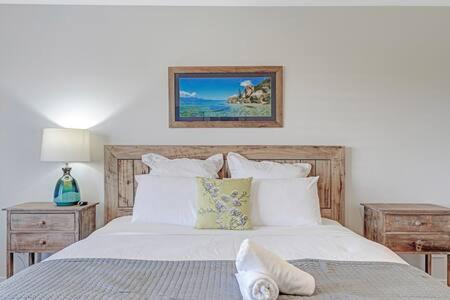 um quarto com uma cama com lençóis brancos e almofadas em Stunning Indoor-Outdoor 4bd-2bth em Surf Beach