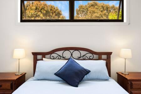 una camera da letto con un letto con cuscini blu e una finestra di 5BR Modern Beach House Oasis a Cowes