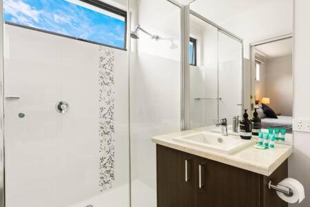 a bathroom with a shower and a sink and a mirror at 5BR Modern Beach House Oasis in Cowes