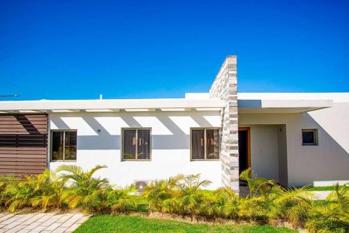 a white house with palm trees in front of it at Beautiful Village 3 bedrooms Furnished Pool residencial Velero punta cana in Punta Cana