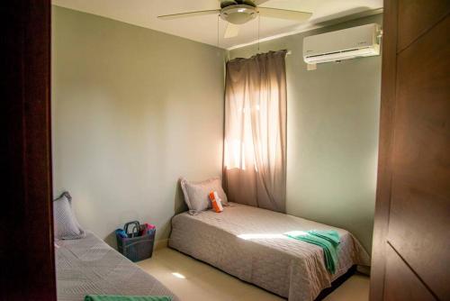 a small bedroom with a bed and a fan at Beautiful Village 3 bedrooms Furnished Pool residencial Velero punta cana in Punta Cana