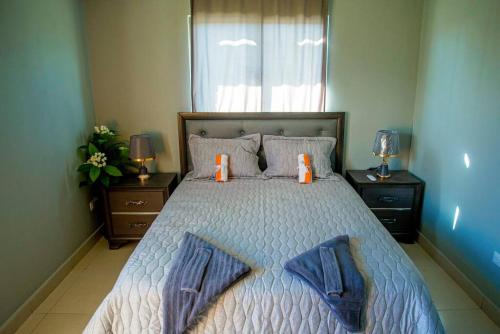 a bedroom with a bed with two orange candles on it at Beautiful Village 3 bedrooms Furnished Pool residencial Velero punta cana in Punta Cana