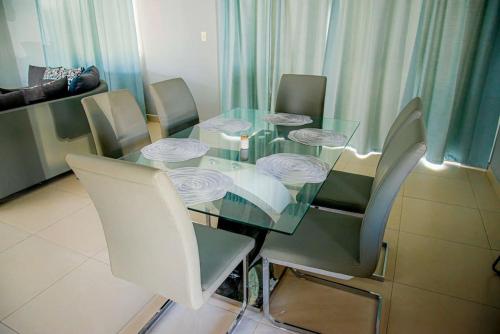a glass dining room table with white chairs around it at Beautiful Village 3 bedrooms Furnished Pool residencial Velero punta cana in Punta Cana