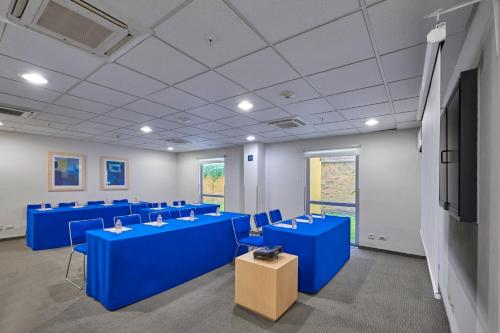 a conference room with blue tables and a flat screen tv at City Express by Marriott Tepotzotlán in Tepotzotlán