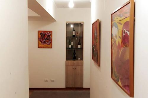 a hallway with paintings and a shelf of wine bottles at Excellent apartment, access to pool, grills, ballroom in Lima