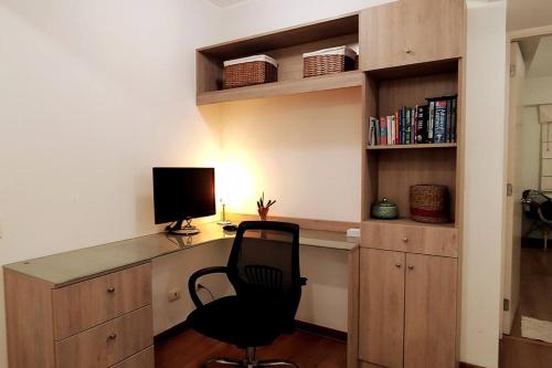 a desk with a computer and a chair in a room at Excellent apartment, access to pool, grills, ballroom in Lima