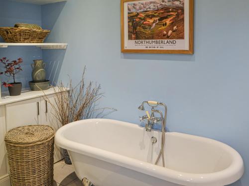 a bath tub in a bathroom with a picture on the wall at The Waiting Room in Falstone