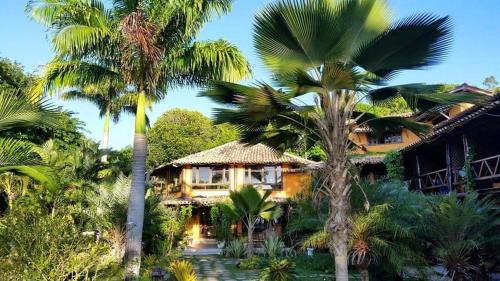 uma casa com palmeiras em frente em pousada mandala em Cumuruxatiba