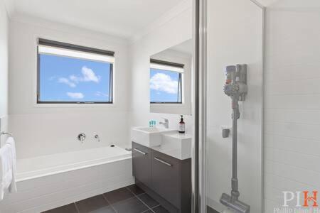 een witte badkamer met een bad en een wastafel bij Townhouse Close to Town Sleeps 6 in Cowes