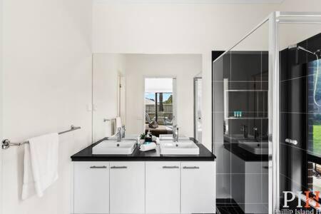 ein weißes Badezimmer mit 2 Waschbecken und einem Spiegel in der Unterkunft Recently build 4BDR Family Home in Quiet Estate in Cowes