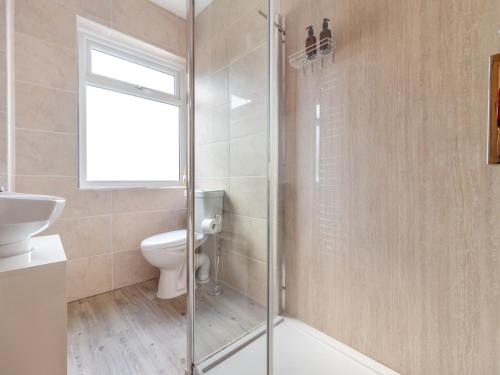 a bathroom with a toilet and a glass shower at Ty Cwtch in Seven Sisters