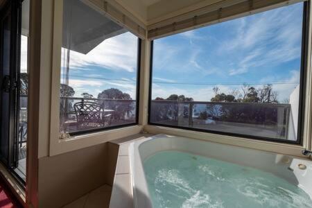a bath tub in a room with two windows at Moonlight Bay and Gallery Ocean View King Suite #3 in Newhaven